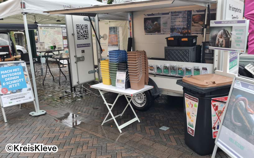 Ein Infostand mit Flyern zur Aufklärung und verschieden farbige Mülleimer.